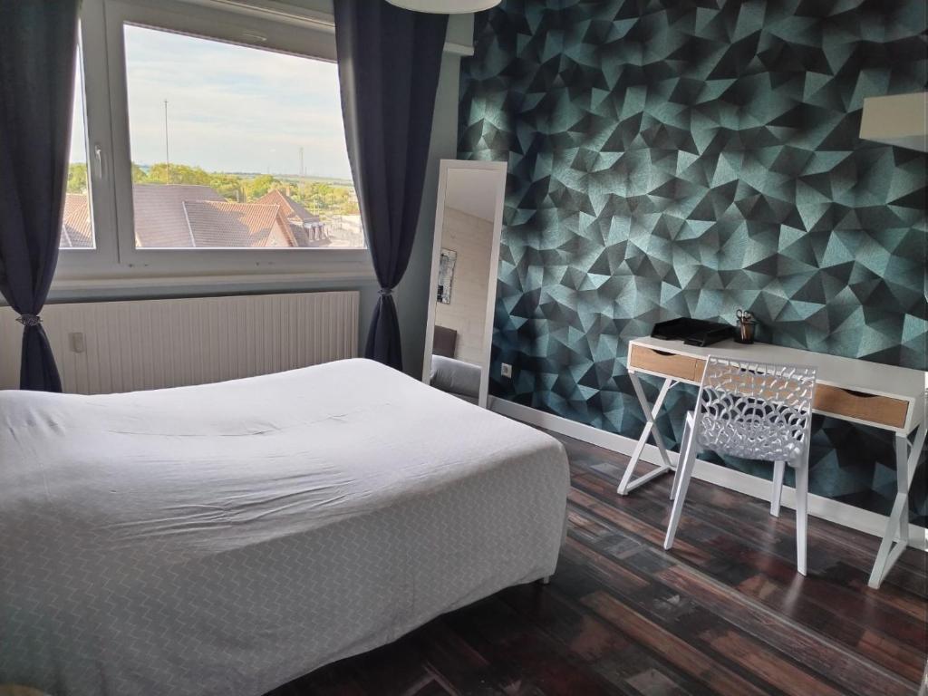 a bedroom with a bed and a desk and a window at L'Europ'appart : Gare, Center parcs, Parc St Croix in Sarrebourg