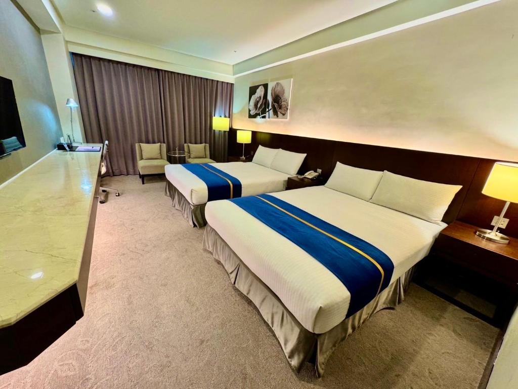 a hotel room with two beds and a desk at HiYesHotel勤天商旅-花蓮館 in Hualien City