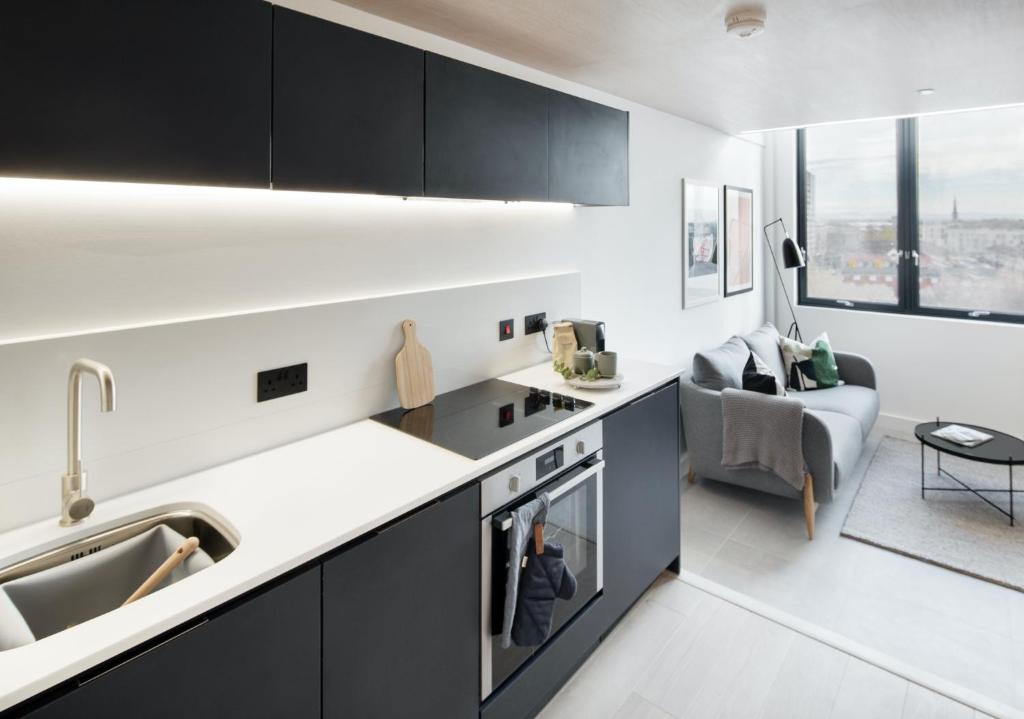 a kitchen with black cabinets and a living room at Modern 1-bed Duplex+Balcony in Manchester