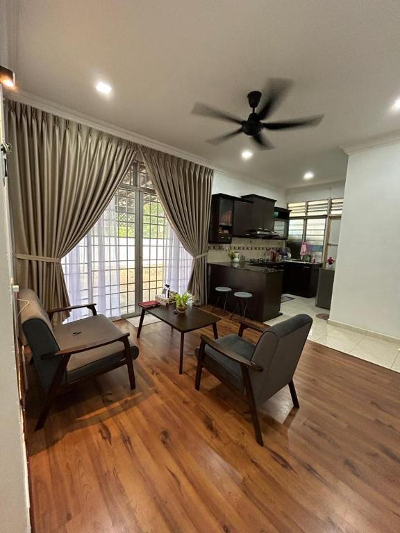 a living room with a ceiling fan and a couch and chairs at Alora Homestay in Alor Setar
