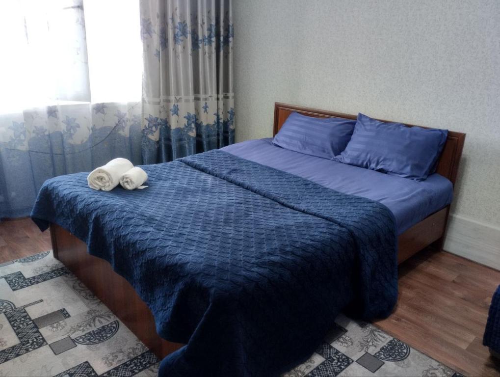 a bedroom with a blue bed with towels on it at Квартира in Taraz