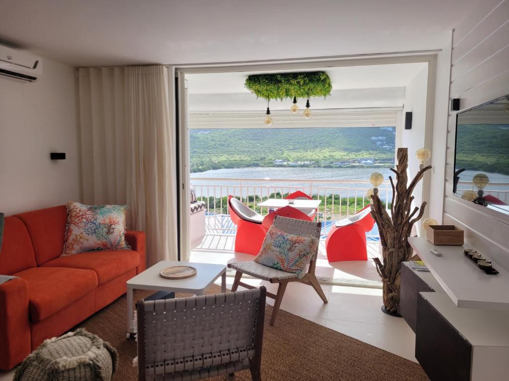 a living room with a red couch and a view of the ocean at Appartement neuf design - Résidence avec piscine in Cul de Sac