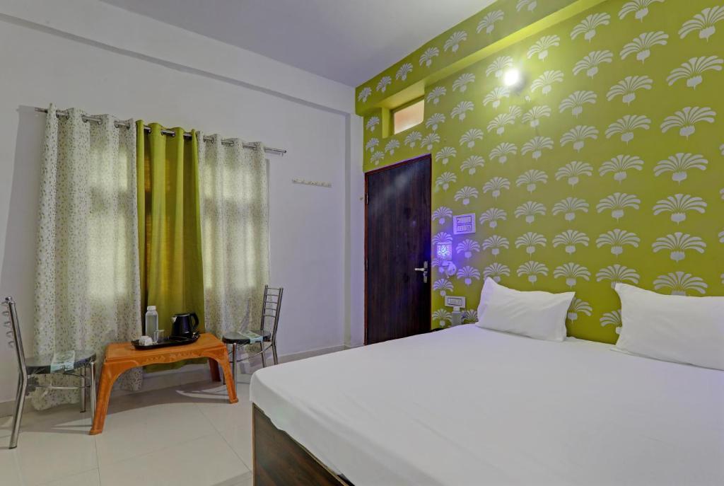 Hotel Surya Inn في Pura Raghunāth: غرفة نوم بسرير ابيض وجدار اخضر