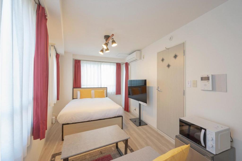 a small room with two beds and a tv at COSMOS REID Minamiazabu in Tokyo
