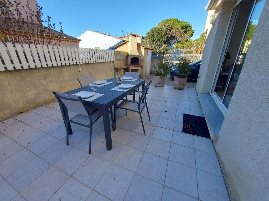 une table noire et des chaises sur une terrasse dans l'établissement Maison T3 Climatisée à 150m de la Plage avec Terrasse et Parking, Tout à Pied! - FR-1-423-307, au Grau-dʼAgde