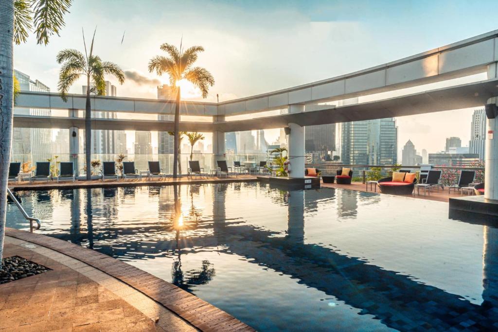 einen Pool auf dem Dach eines Gebäudes mit Palmen in der Unterkunft Centara Grand At CentralWorld in Bangkok