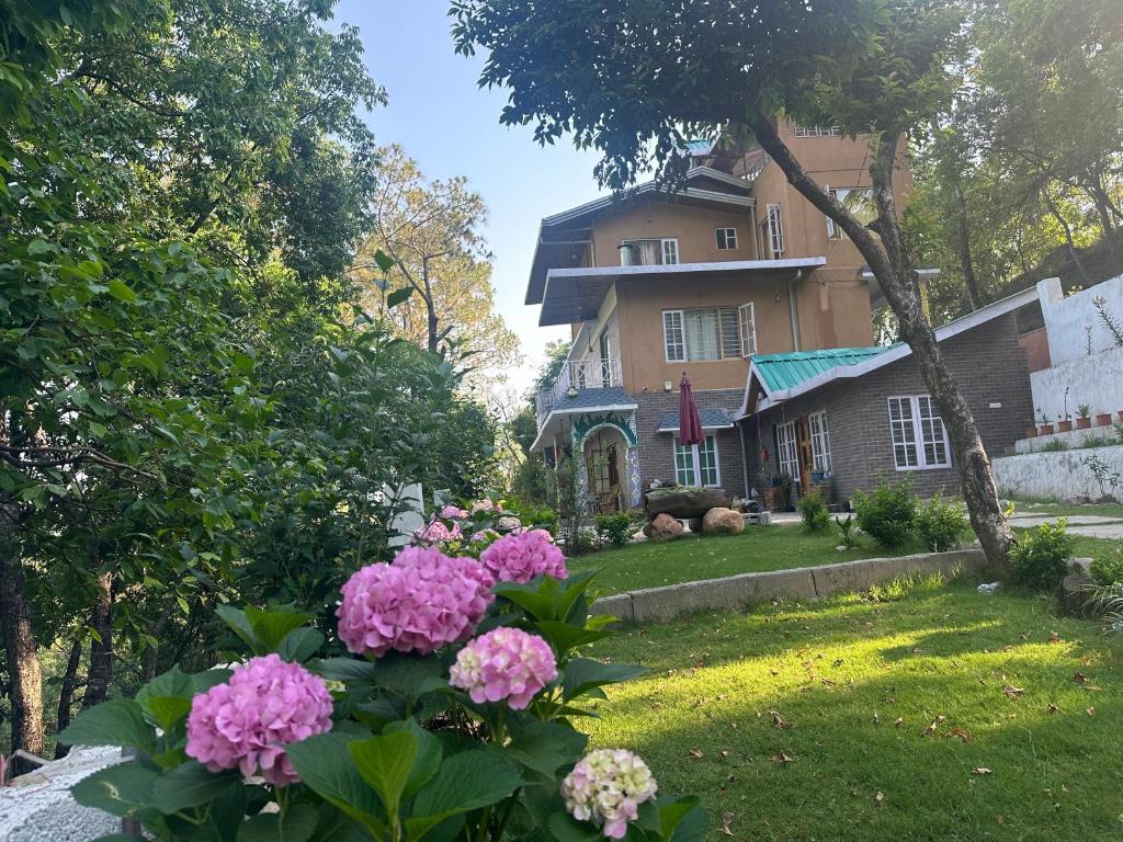a house with pink flowers in the yard at Kut House in Pālampur