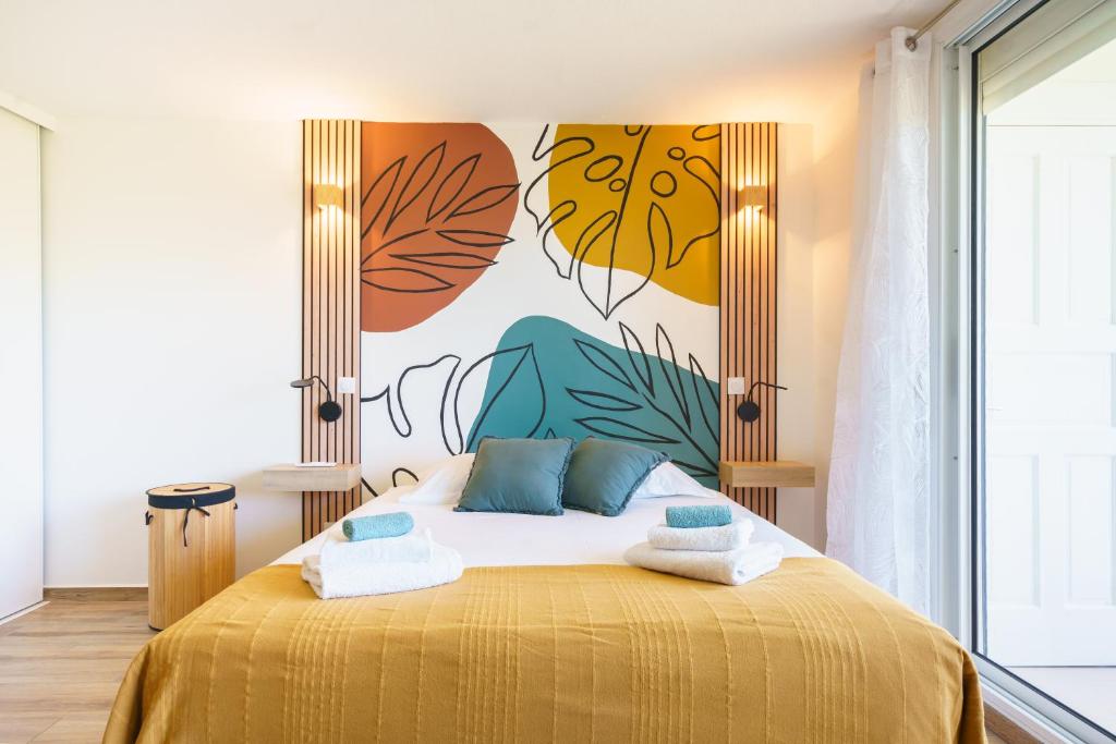 a bedroom with a yellow bed with a painting on the wall at Studio neuf et cosy proche des plages - L'Alamanda in Le Gosier