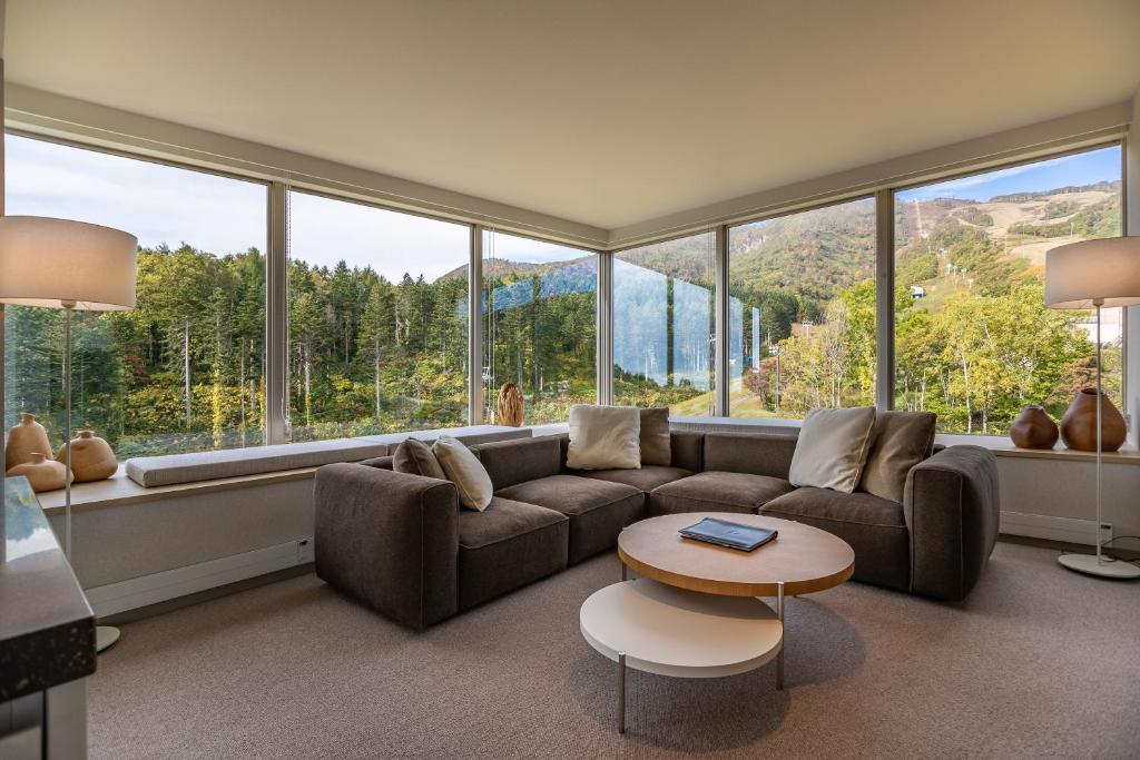 a living room with a couch and a table and large windows at The Maples Niseko in Kutchan