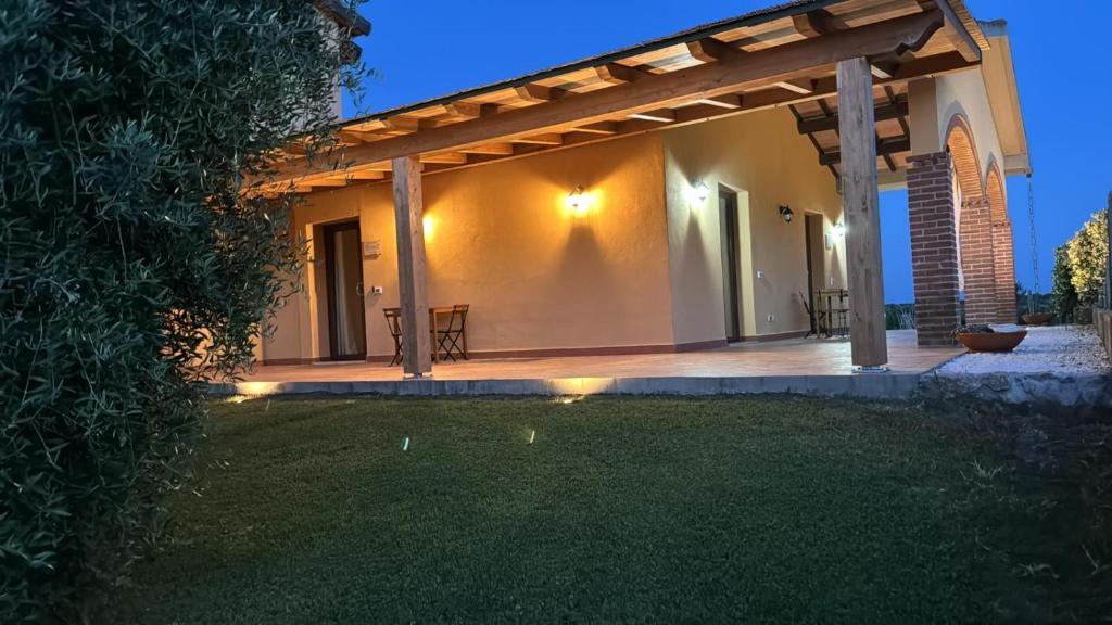 Una casa con una pérgola en un patio por la noche. en Agriturismo Il Giardino Degli Olivi Appartamenti, en Castiglione della Pescaia