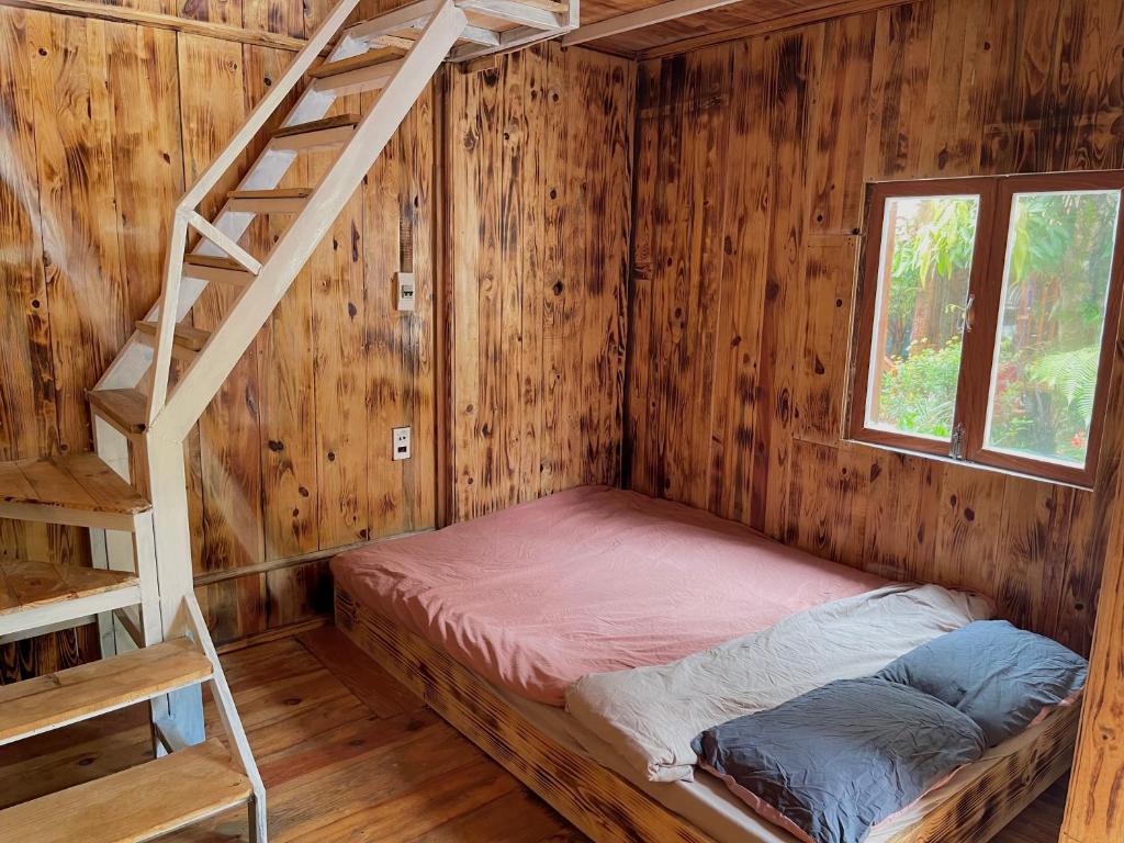 uma cama num quarto de madeira com uma escada em 1996 Homestay Măng Đen em Kon Von Kla