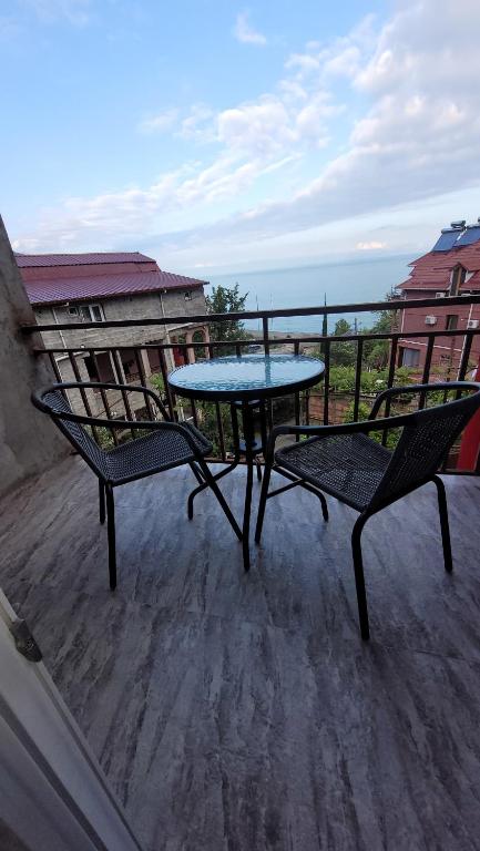 a table and two chairs on a balcony with the ocean at PharphalInn in Batumi
