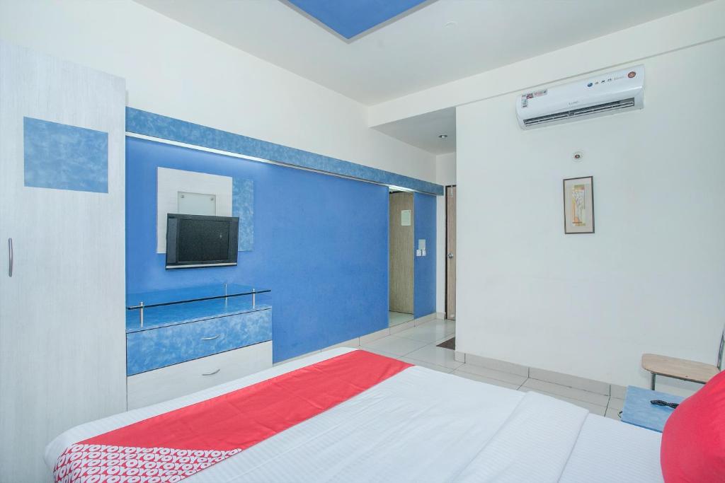 Cette chambre comprend un lit et une télévision murale. dans l'établissement OYO 8501 ABHIMAANI COMFORTS, à Bangalore