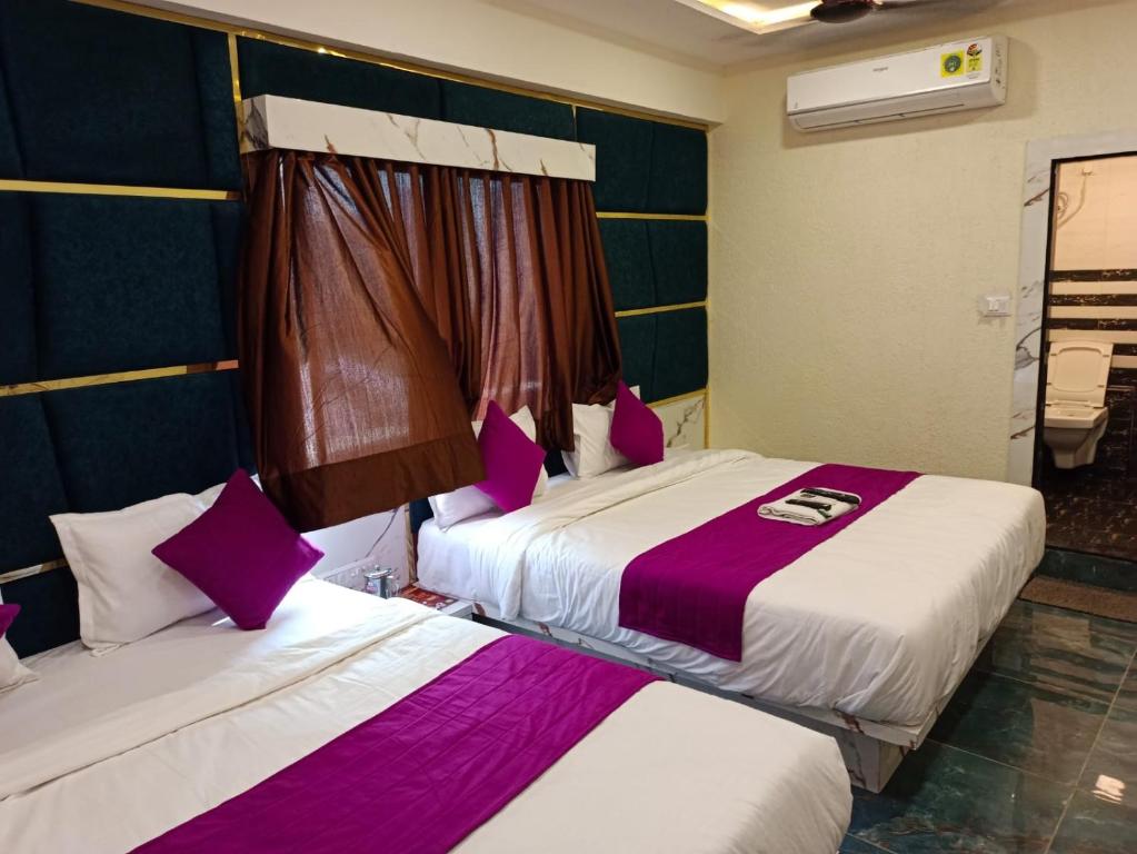 duas camas num quarto com lençóis roxos e brancos em Hotel Karnavati em Ahmedabad