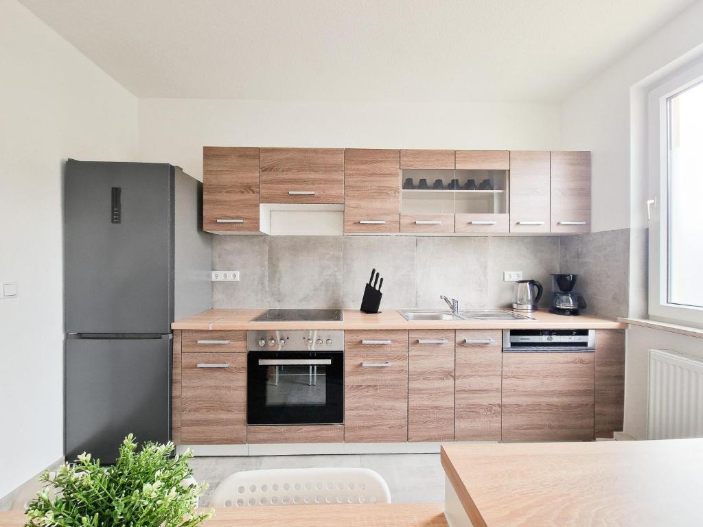 La cuisine est équipée d'armoires en bois et d'un réfrigérateur en acier inoxydable. dans l'établissement RAJ Living - 4 Zimmer Wohnung - 25 Min zur Messe DUS, à Krefeld