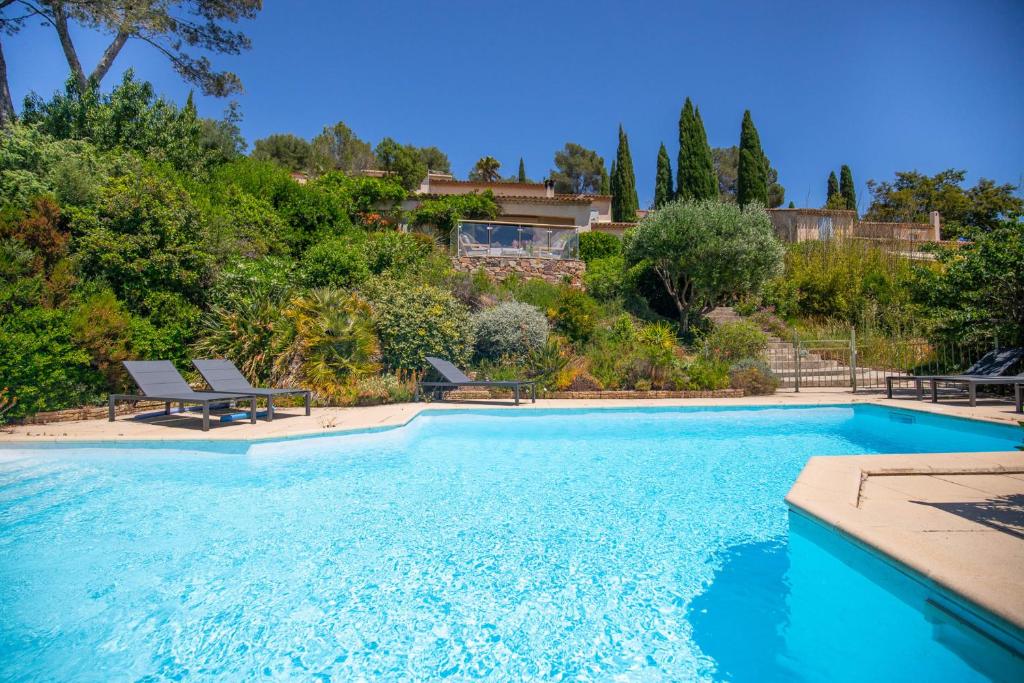 une piscine avec deux chaises et une maison dans l'établissement Villa 10 people with private pool near Saint-Tropez, à Roquebrune-sur Argens