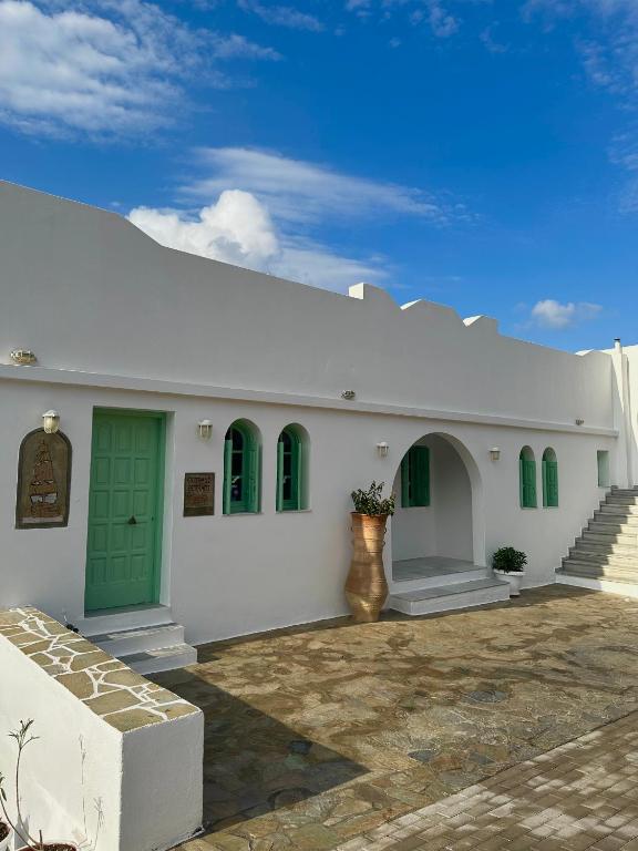 a white building with a green door and stairs at Hotel Petradi in Ios Chora