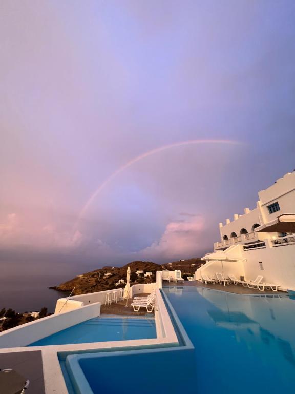 a rainbow over a swimming pool with a hotel at Hotel Petradi in Ios Chora