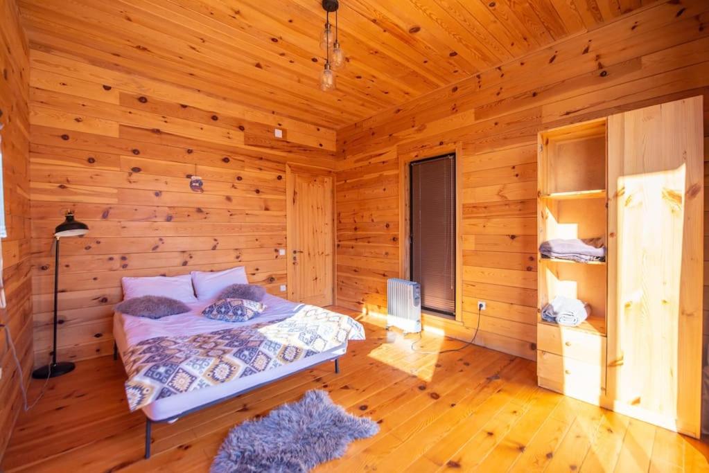 Un dormitorio con una cama en una cabaña de troncos en Ideal six-person villa for large families with pets, featuring barbecue and spacious yard Svaneti Сountryside 1, en Shkaleri