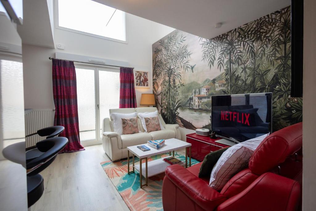 uma sala de estar com um sofá vermelho e uma televisão em DUPLEX Luxury-Appart - DYSNEY LAND PARIS em Bussy-Saint-Georges