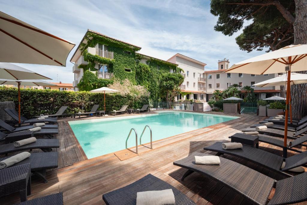einen Pool mit Stühlen und Sonnenschirmen neben einem Gebäude in der Unterkunft Marina Garden Hotel in Marciana Marina