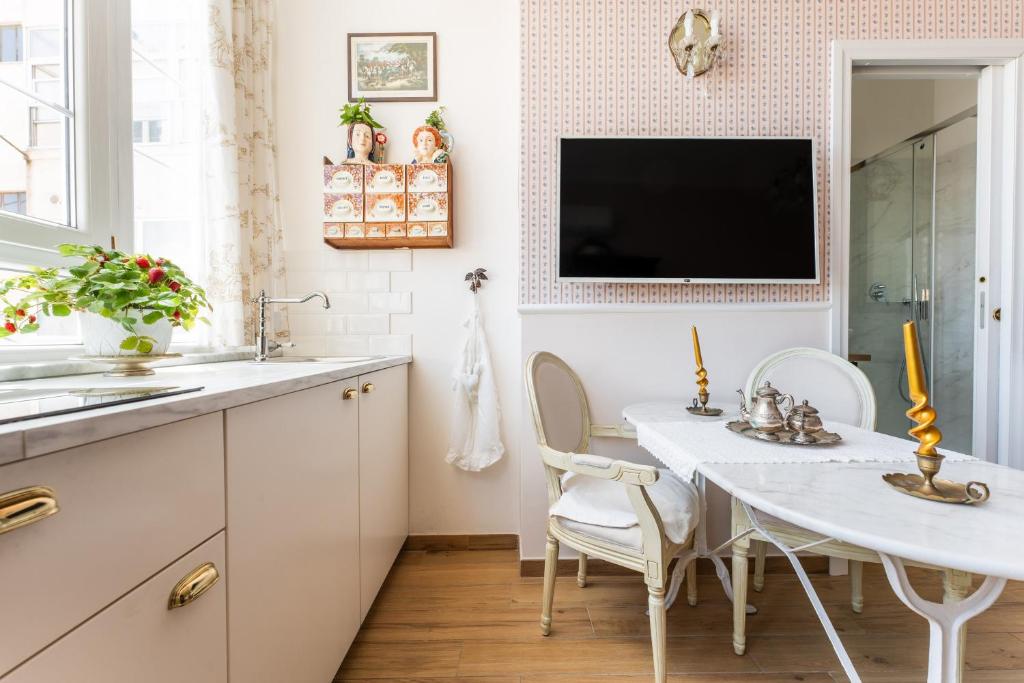 TV y cocina con mesa y sillas blancas. en Dependance '800, en Cagliari