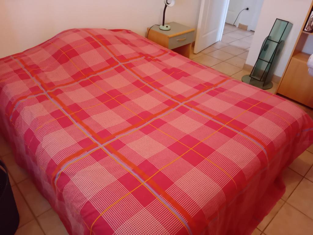 a red plaid blanket on a bed in a room at une Chambre meublé chez habitant in Roézé-sur-Sarthe