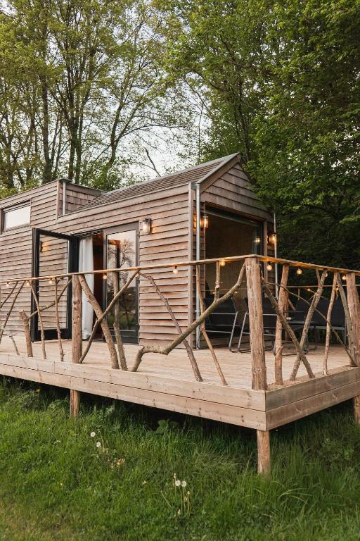 eine Holzhütte mit einer großen Terrasse im Gras in der Unterkunft Ekko tiny house in Philippeville