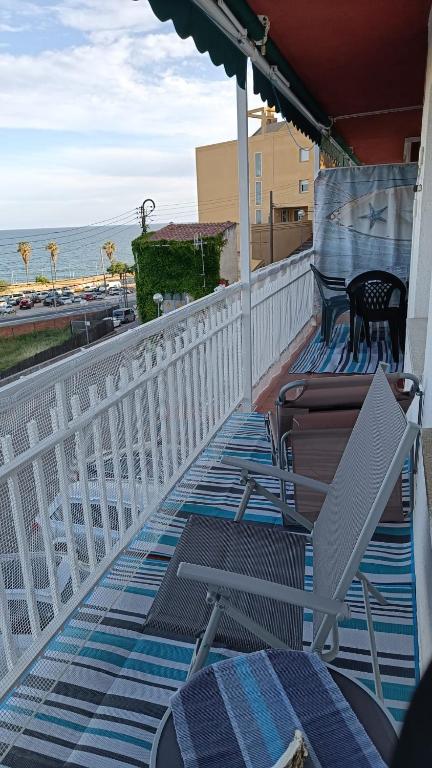 a balcony with chairs and an umbrella and the ocean at Canet playa y centro con free wifi in Canet de Mar