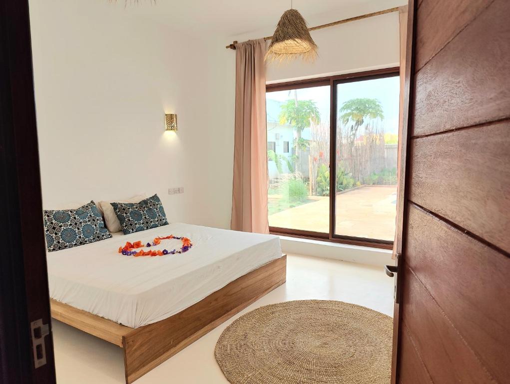 a bedroom with a bed and a large window at Luxury White Villa in Nungwi