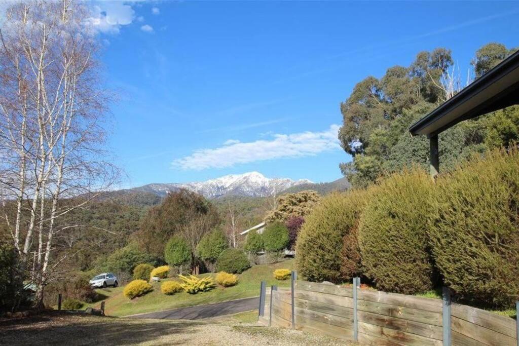 una casa con jardín y montañas en el fondo en Buller House Merrijig, en Merrijig