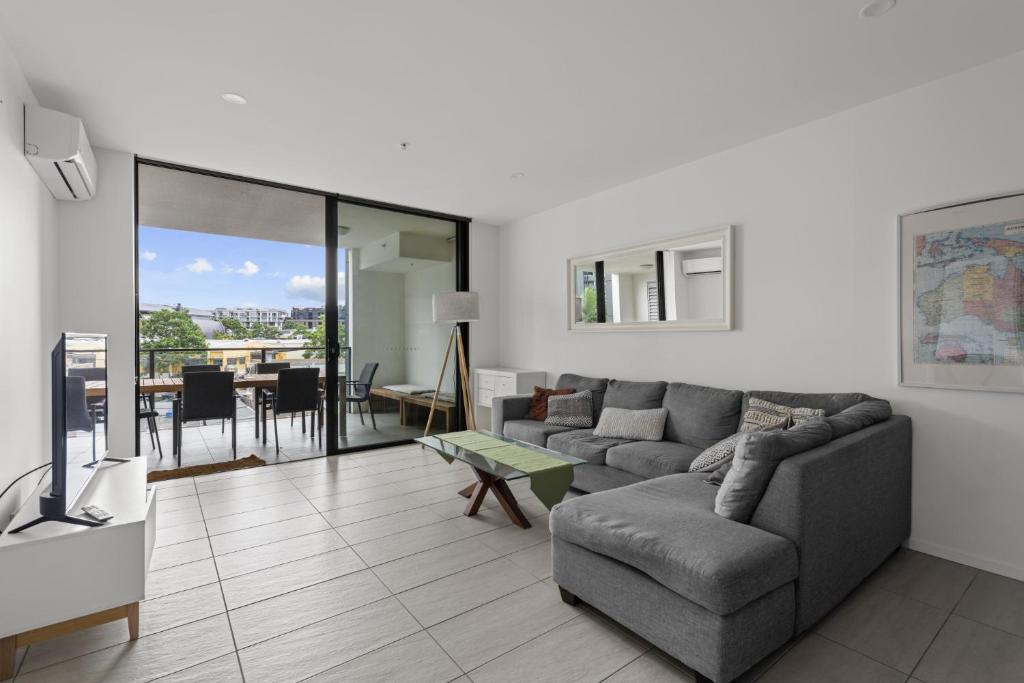 a living room with a couch and a table at Sleek City Apartment with Parking and Balcony in Brisbane