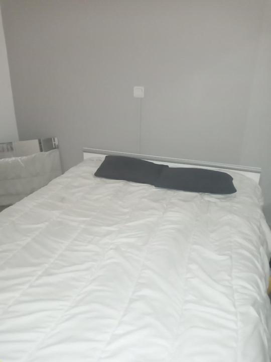 - un lit blanc avec un oreiller noir dans l'établissement J.O STADE, à Saint-Denis