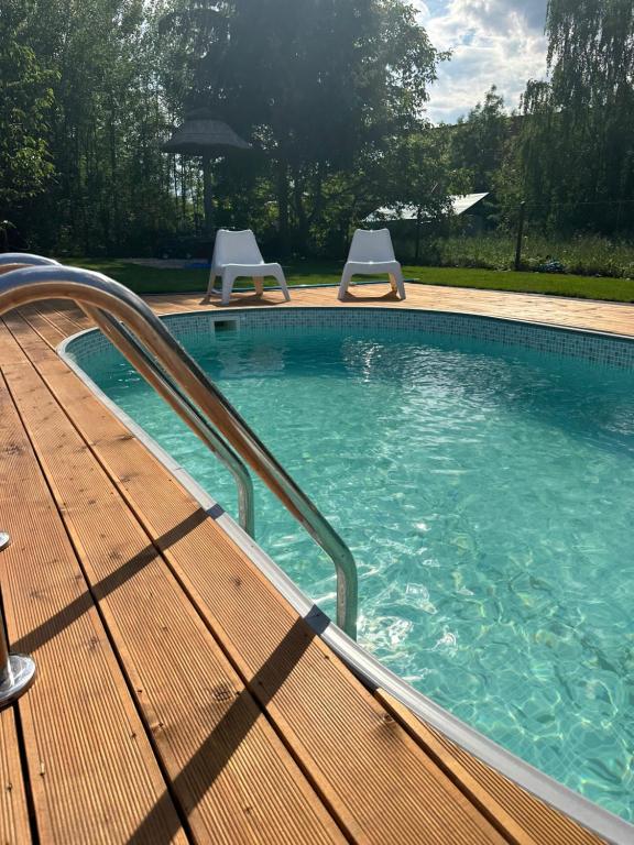 a swimming pool with a wooden bench and two chairs at Dom mazurski z basenem in Rydzewo