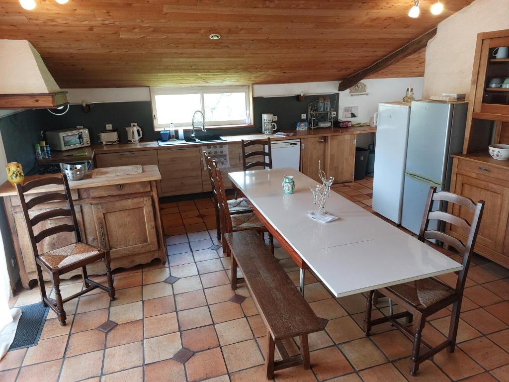 eine Küche mit Tisch und Stühlen und einem Kühlschrank in der Unterkunft maison du 13eme siècles in La Genétouze