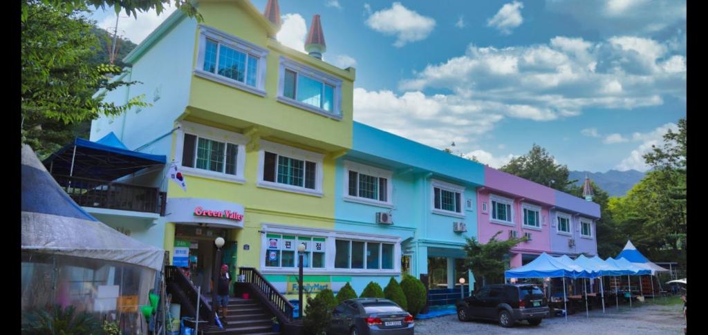 un edificio colorido con coches estacionados frente a él en Green Valley en Sancheong