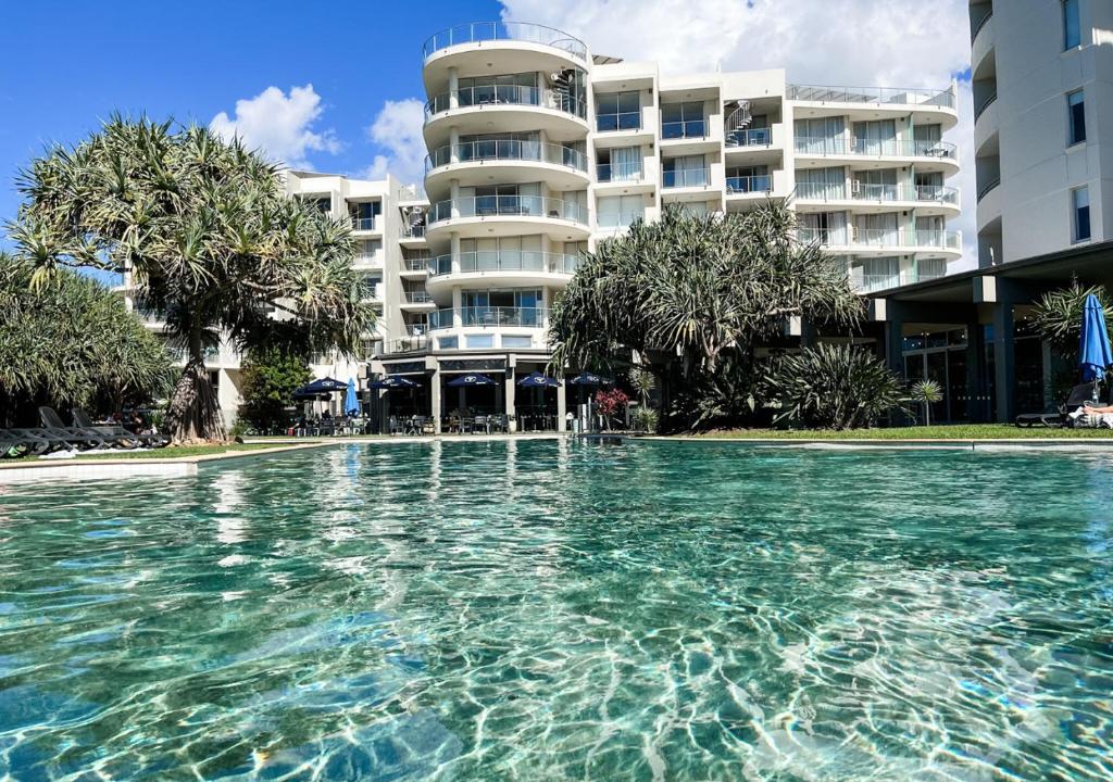 une piscine en face d'un grand bâtiment dans l'établissement Privately Owned Hotel Room in Beachside Resort - Sleeps 4, à Marcoola