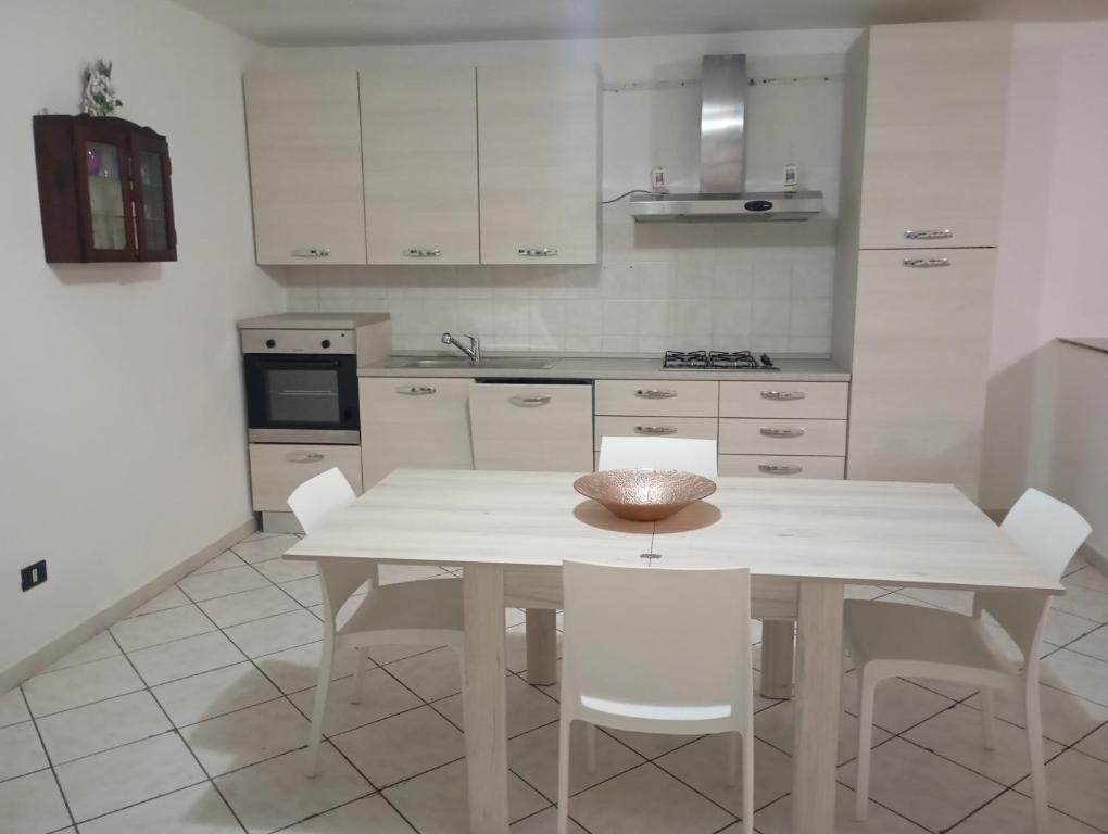 cocina blanca con mesa blanca y sillas blancas en Casa vacanze da viola, en Ugento