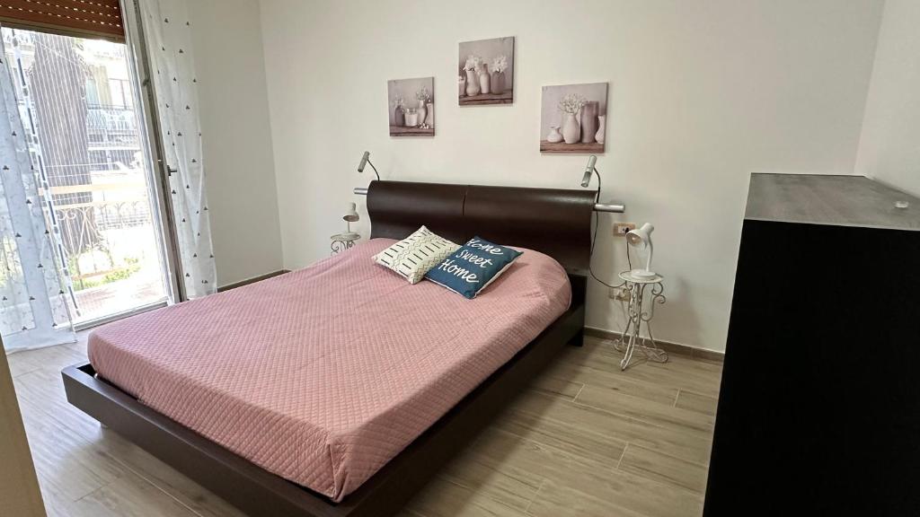 um quarto com uma cama com lençóis e almofadas cor-de-rosa em casa Mari, 250 mt dalle spiagge em Diano Marina