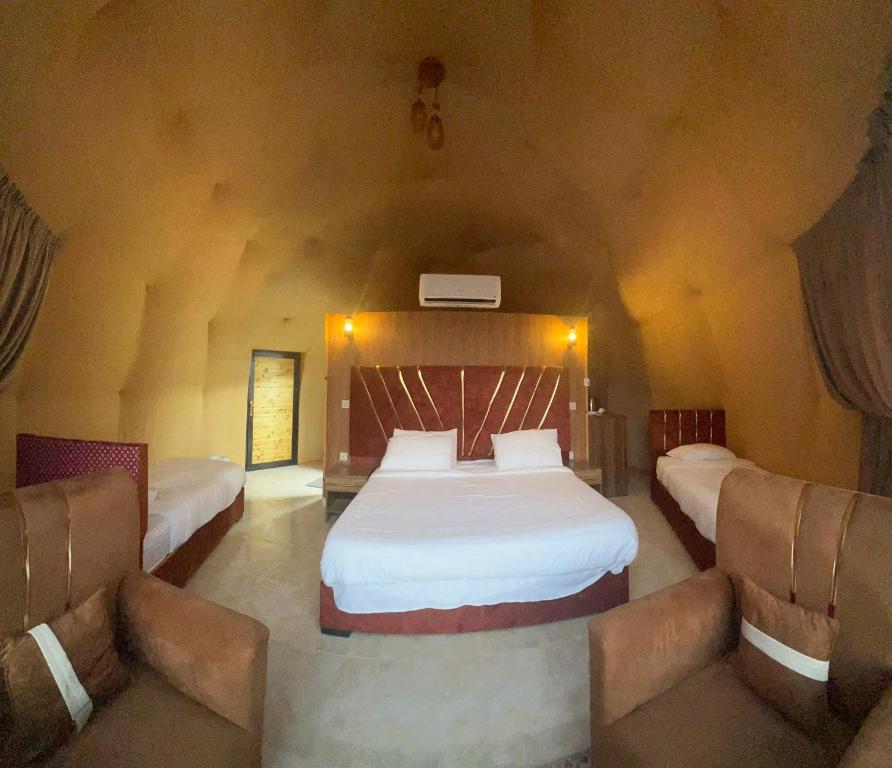 a bedroom with two beds and a couch at Golden Gate Luxury Camp in Wadi Rum
