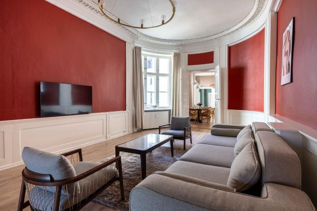a living room with red walls and a couch and chairs at Deluxe Apartment at Perfect Location in Copenhagen