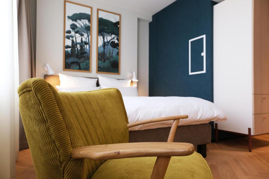 - une chambre avec un lit et une chaise verte dans l'établissement Hood House Kassel, à Cassel