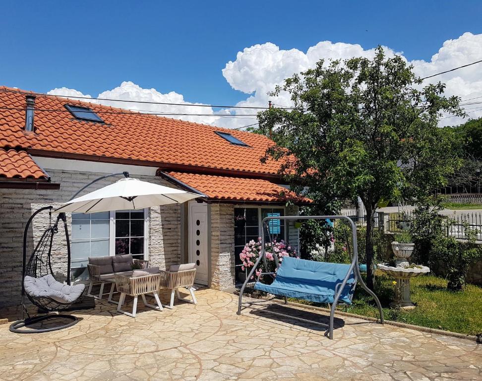 a patio with a swing and an umbrella at Kali in Kukuljanovo
