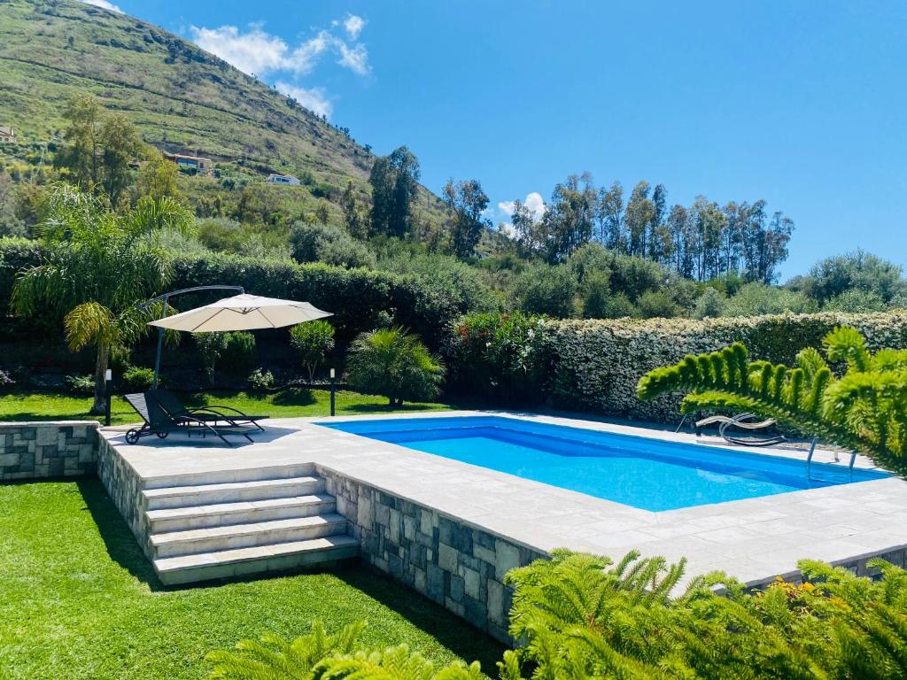 a swimming pool in a garden with an umbrella at Relaxing Villa Cefalù - Private Pool & Beach Walk by flAle's in Cefalù