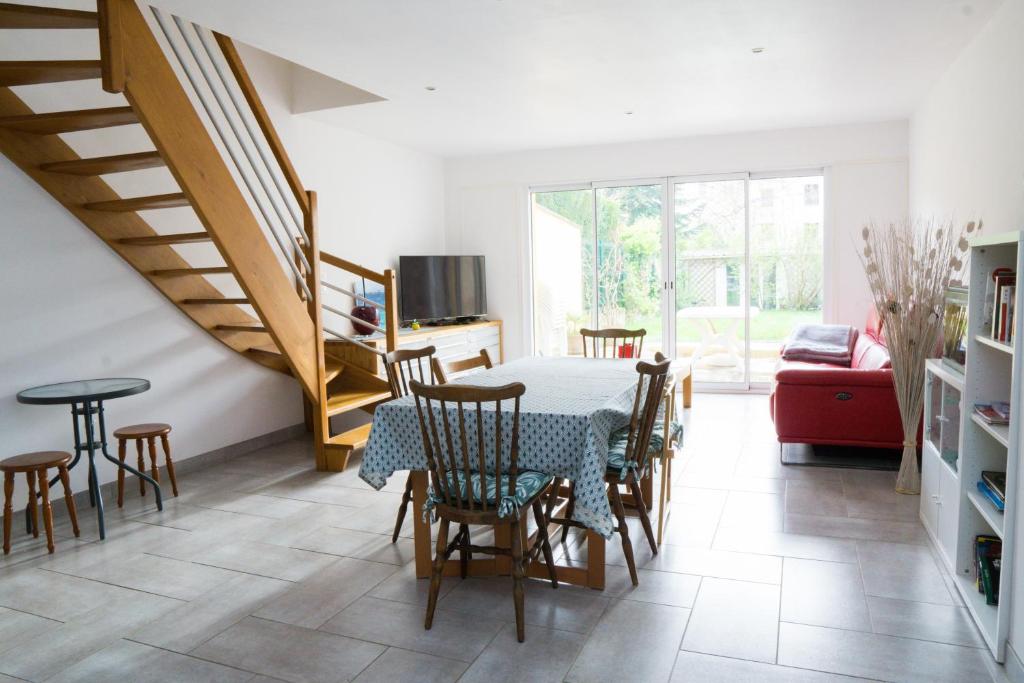 een eetkamer met een tafel en stoelen en een trap bij EXIGEHOME - Maison à 2 pas de la foret - 30min de Versailles in Vélizy-Villacoublay