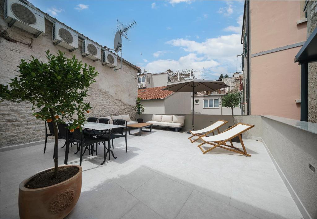 a patio with a table and chairs and a tree at SAMM Apartments Šibenik in Šibenik