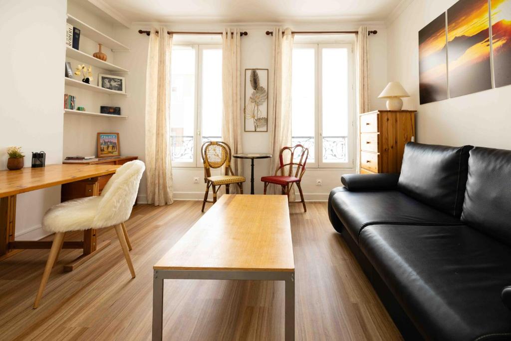 ein Wohnzimmer mit einem schwarzen Sofa und einem Tisch in der Unterkunft Well located apartment in Paris in Paris