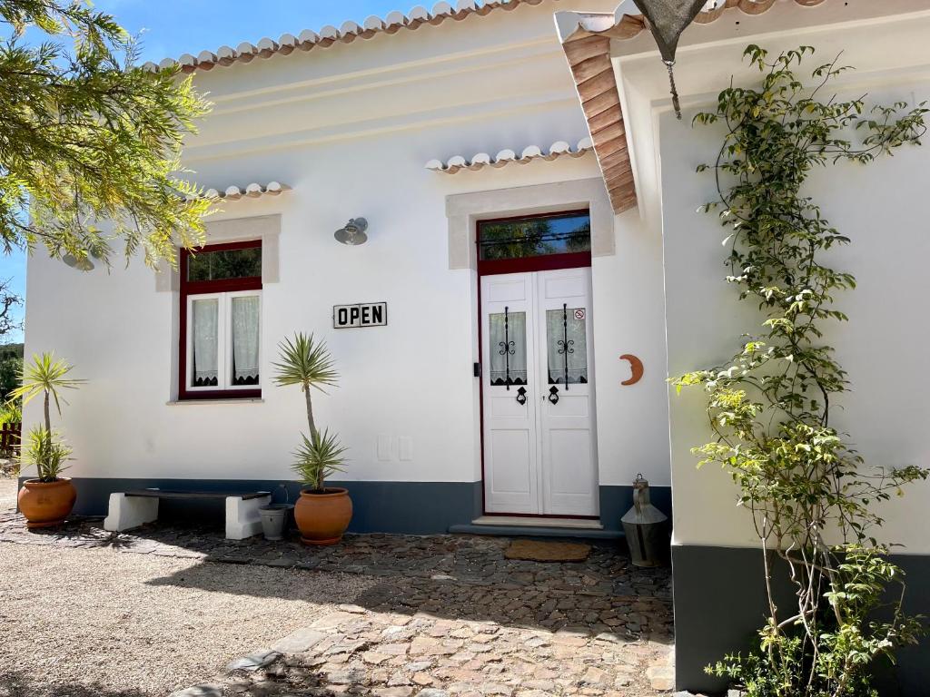 una casa blanca con puerta y macetas en Casa dos Cantoneiros, en Aljezur
