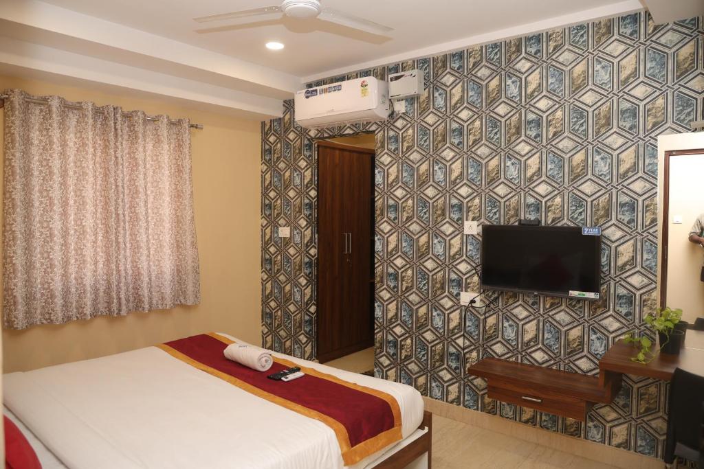 a bedroom with a bed and a tv on a wall at virat inn in Bangalore