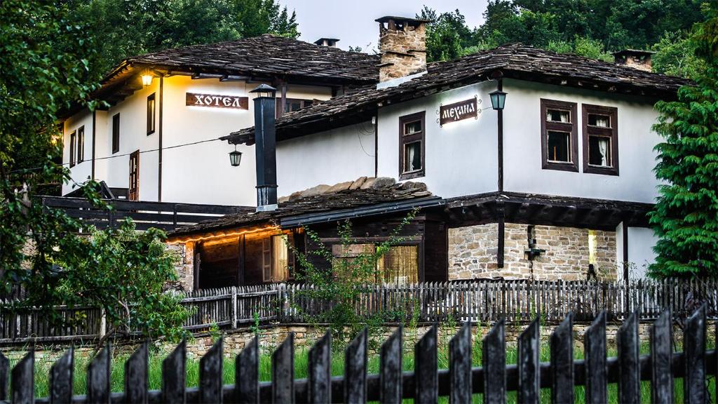 une vieille maison avec une clôture devant elle dans l'établissement Strannopriemnitsa Guest House, à Bozhentsi